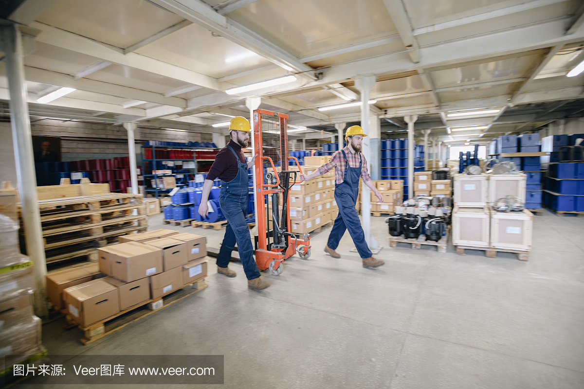 在工厂处理重产品时,严肃的强泵房同事一起推着装载车